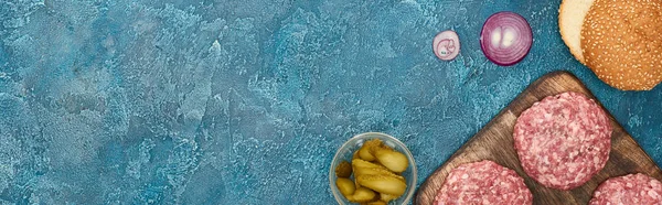 Top view of fresh burger ingredients on blue textured surface, panoramic shot — Stock Photo