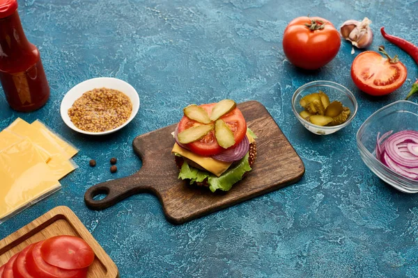 Ingredientes frescos de la hamburguesa en la superficie de textura azul - foto de stock