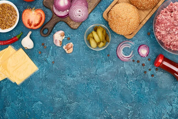Vista superior de ingredientes de hambúrguer fresco na superfície texturizada azul — Fotografia de Stock