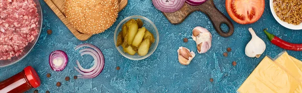 Top view of fresh burger ingredients on blue textured surface, panoramic shot — Stock Photo