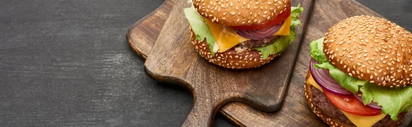 Deliciosas hamburguesas frescas con queso sobre tablas de madera, plano panorámico - foto de stock