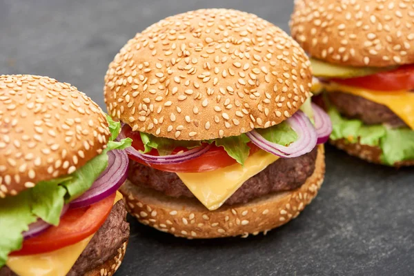 Vue rapprochée de délicieux cheeseburgers frais sur table en bois — Photo de stock