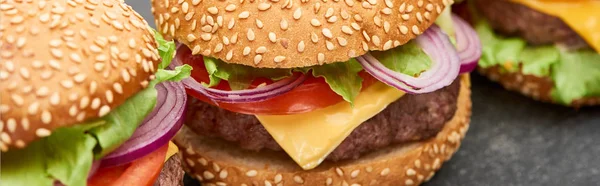 Vista de cerca de deliciosas hamburguesas con queso fresco en la mesa de madera, plano panorámico - foto de stock