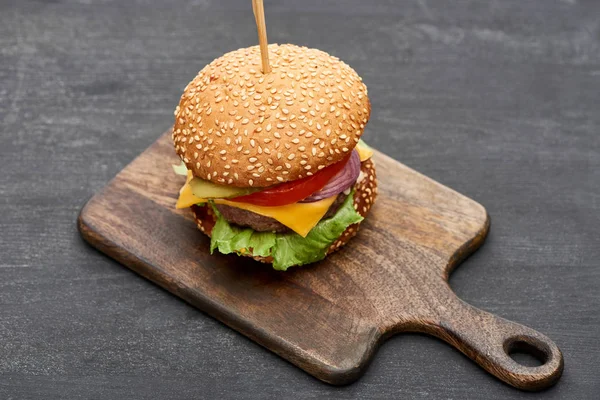 Delicious fresh cheeseburger on wooden board — Stock Photo
