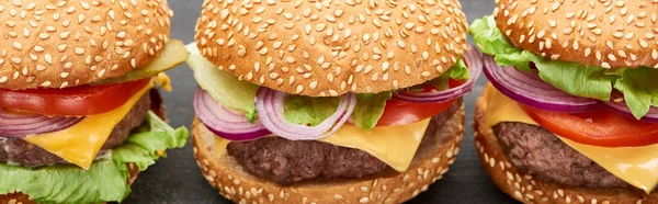 Vista de cerca de deliciosas hamburguesas con queso fresco en la mesa negra, plano panorámico - foto de stock