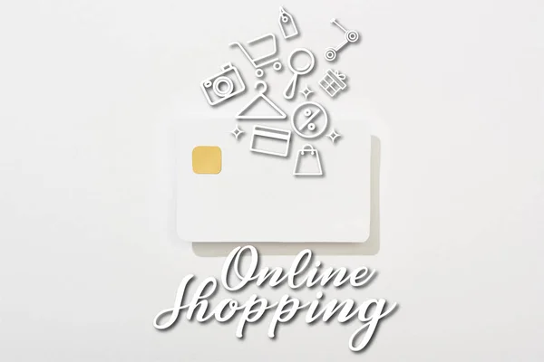 Верхний вид пустой кредитной карты на белом фоне с иллюстрацией покупок в Интернете — стоковое фото