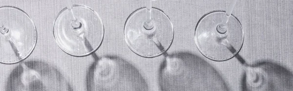 Top view of wine glasses on grey surface with shadow, panoramic shot — Stock Photo