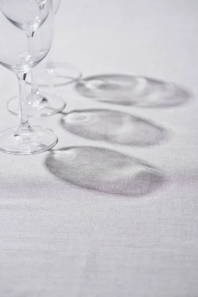 Прозорі келихи для вина з тіні на сірій скатертині — стокове фото