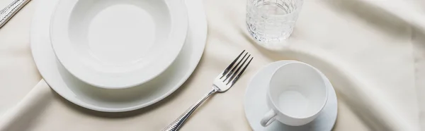 High angle view of dinnerware with glass and coffee cup on white tablecloth, panoramic shot — Stock Photo