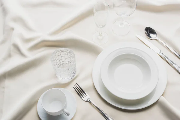 High angle view of dinnerware with glasses and coffee cup on white tablecloth — Stock Photo