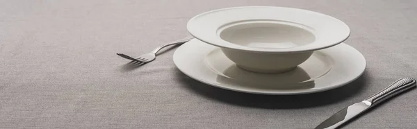 Two plates and cutlery on grey surface, panoramic shot — Stock Photo