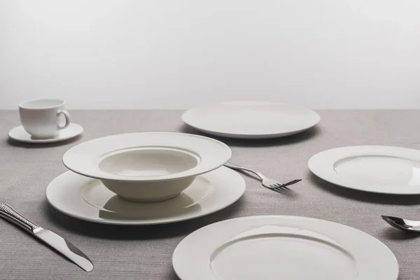 Порожній посуд з чашкою кави на скатертині на сірому фоні — стокове фото
