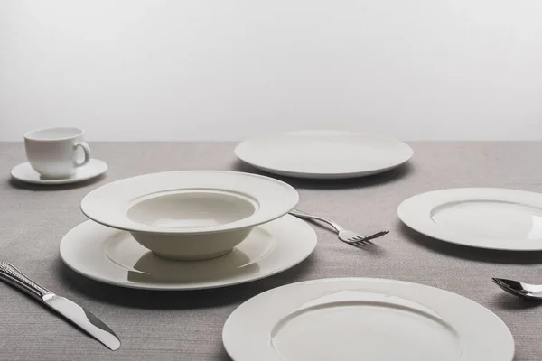 Empty tableware with coffee cup on tablecloth on gey background — Stock Photo