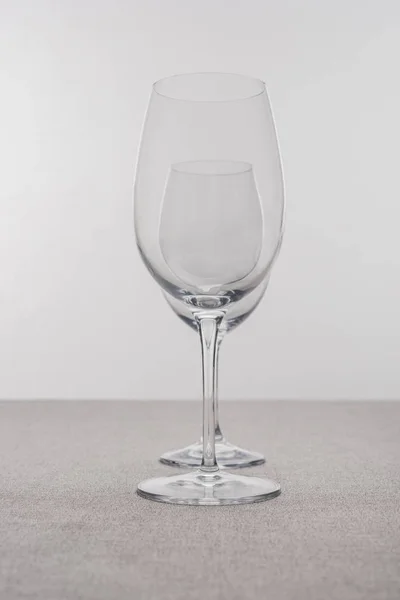 Selective focus of transparent wine glasses on tablecloth isolated on grey — Stock Photo