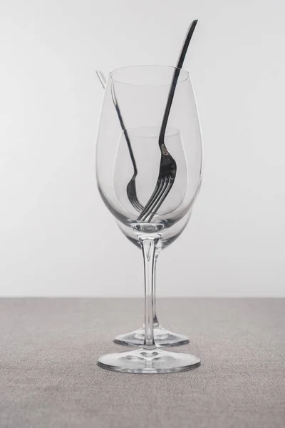 Вибірковий фокус виделки в прозорих келихах для вина на скатертині ізольовані на сірому — стокове фото