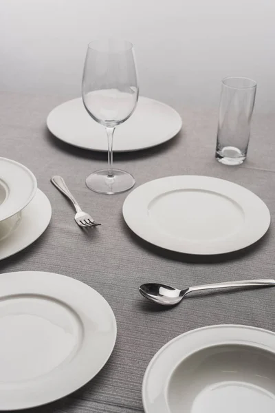 Serving dinnerware with empty glasses on grey surface — Stock Photo