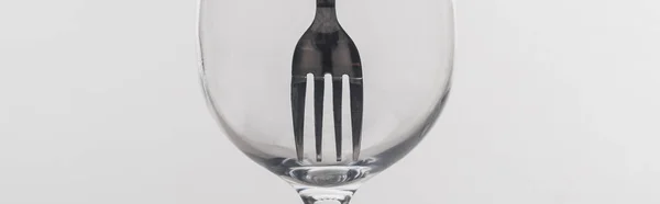 Панорамный снимок вилки в прозрачном бокале вина, изолированный на сером — стоковое фото
