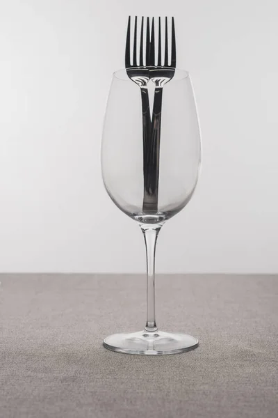 Gabeln im transparenten Weinglas auf Tischdecke isoliert auf grau — Stockfoto