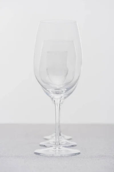 Fila di calici da vino trasparenti su panno isolato su grigio — Foto stock