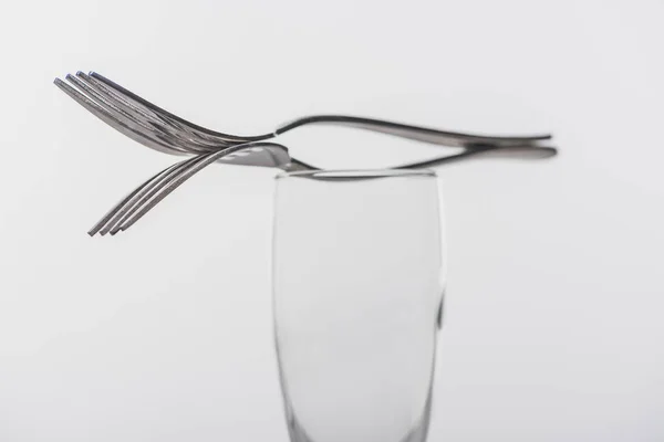 Selective focus of forks on clear champagne glass isolated on grey — Stock Photo