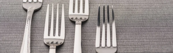 Vista de cerca de tenedores brillantes en tela gris, plano panorámico - foto de stock