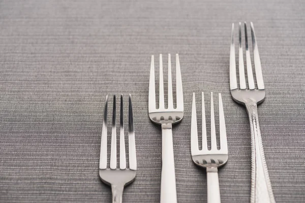 Close up view of shiny forks on grey tablecloth — Stock Photo