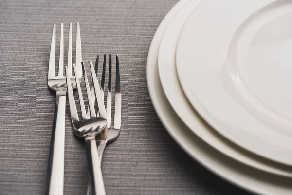 Empty plates with forks on grey linen tablecloth — Stock Photo