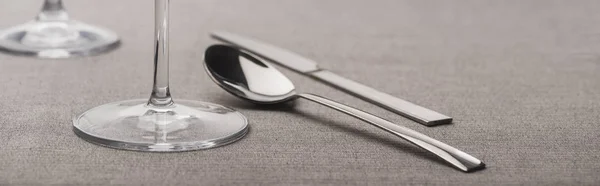 Spoon and knife near wine glasses on grey surface, panoramic shot — Stock Photo