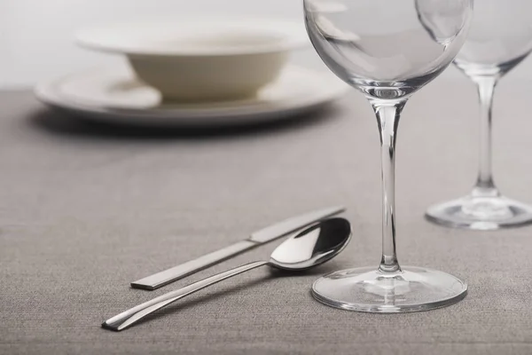 Foco seletivo de talheres perto de copos de vinho claros na toalha de mesa — Fotografia de Stock