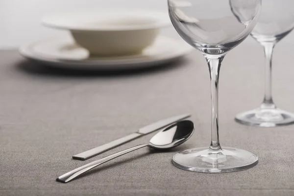 Enfoque selectivo de cubiertos cerca de copas de vino claras en mantel - foto de stock