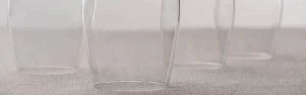 Panoramic shot of clear wine glasses on tablecloth isolated on grey — Stock Photo