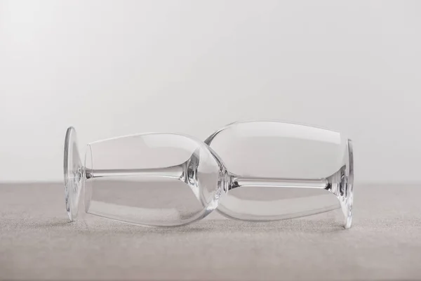 Два прозрачных бокала вина на ткани, изолированные на сером — стоковое фото
