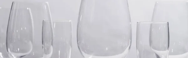 Panoramic shot of shiny glasses isolated on grey — Stock Photo