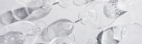 Top view of clear glasses with shadow on grey cloth, panoramic shot — Stock Photo