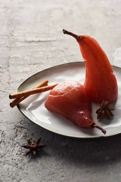 Delicious pear in wine with cinnamon and anise on plate on grey concrete surface — Stock Photo