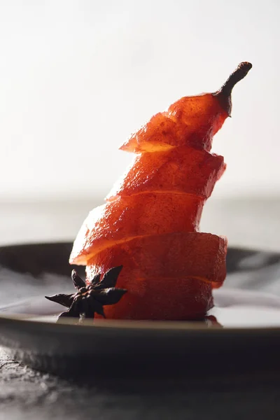 Vista de cerca de la deliciosa pera en rodajas en vino con anís en el plato - foto de stock