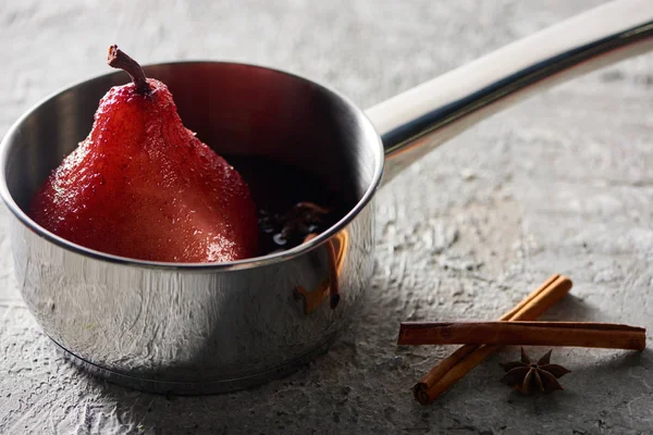 Délicieuse poire dans le vin dans une cocotte près de la cannelle et de l'anis sur une surface en béton gris — Photo de stock