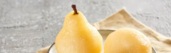 Delicious pear in wine served on plate on napkin on grey concrete surface, panoramic shot — Stock Photo