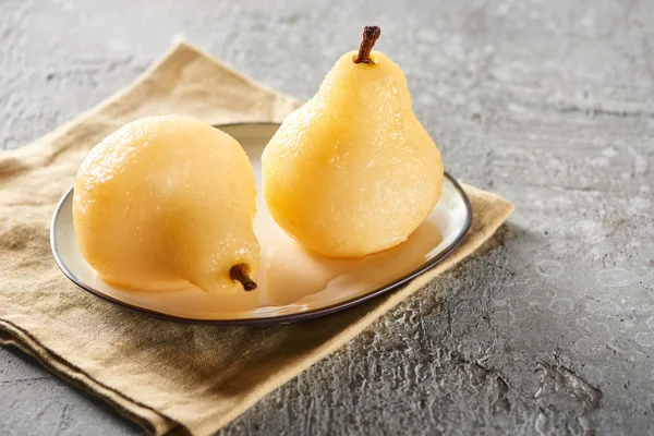 Delicious pear in wine served on plate on napkin on grey concrete surface — Stock Photo