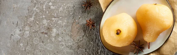 Top view of delicious pear in wine with anise served on plate on napkin on grey concrete surface, panoramic shot — Stock Photo