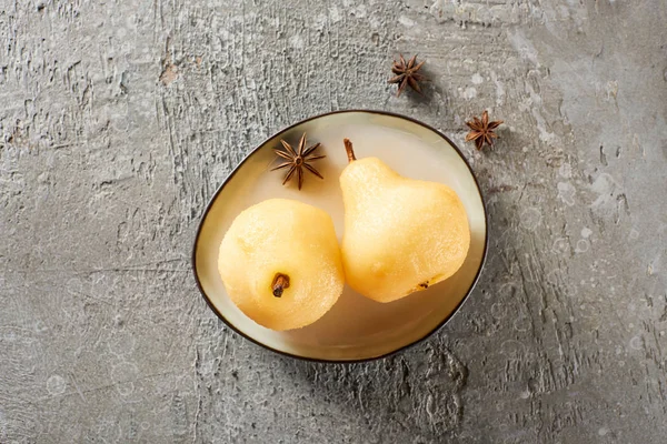 Vue de dessus de délicieuse poire dans le vin servi avec de l'anis sur une assiette sur une surface en béton gris — Photo de stock