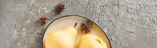 Top view of delicious pear in wine served with anise on plate on grey concrete surface, panoramic shot — Stock Photo