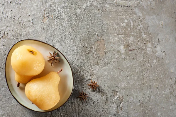 Vue de dessus de délicieuse poire dans le vin servi avec de l'anis sur une assiette sur une surface en béton gris — Photo de stock