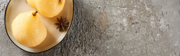Vue de dessus de délicieuse poire dans le vin servi avec de l'anis sur une assiette sur une surface en béton gris, vue panoramique — Photo de stock