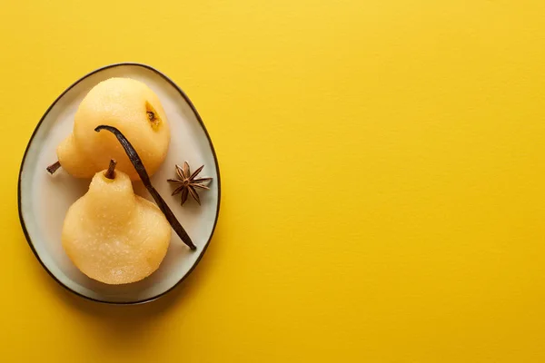 Vue du dessus de délicieuse poire dans le vin avec de l'anis sur assiette sur fond jaune — Photo de stock