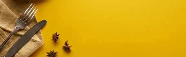 Vue du dessus de l'anis près des couverts sur serviette beige sur fond jaune, vue panoramique — Photo de stock