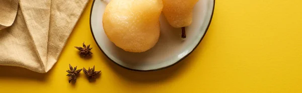 Vue du dessus de délicieuse poire dans le vin avec de l'anis sur l'assiette près de la serviette sur fond jaune, panoramique — Photo de stock