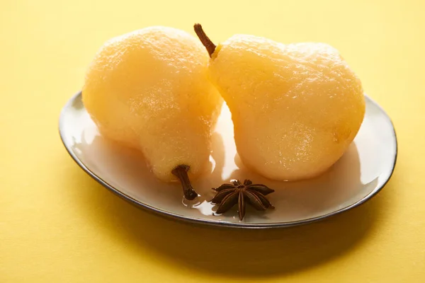 Delicious pear in wine on plate with anise on yellow background — Stock Photo