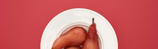 Top view of delicious pears in wine on plate on red background, panoramic shot — Stock Photo