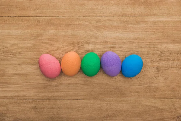 Верхний вид радужных окрашенных пасхальных яиц на деревянном столе — стоковое фото